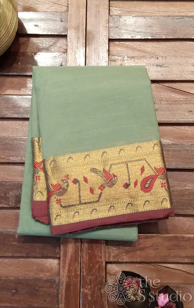 Light green kanchi cotton saree with brown selvedge and a zari border adorned with peacock motifs