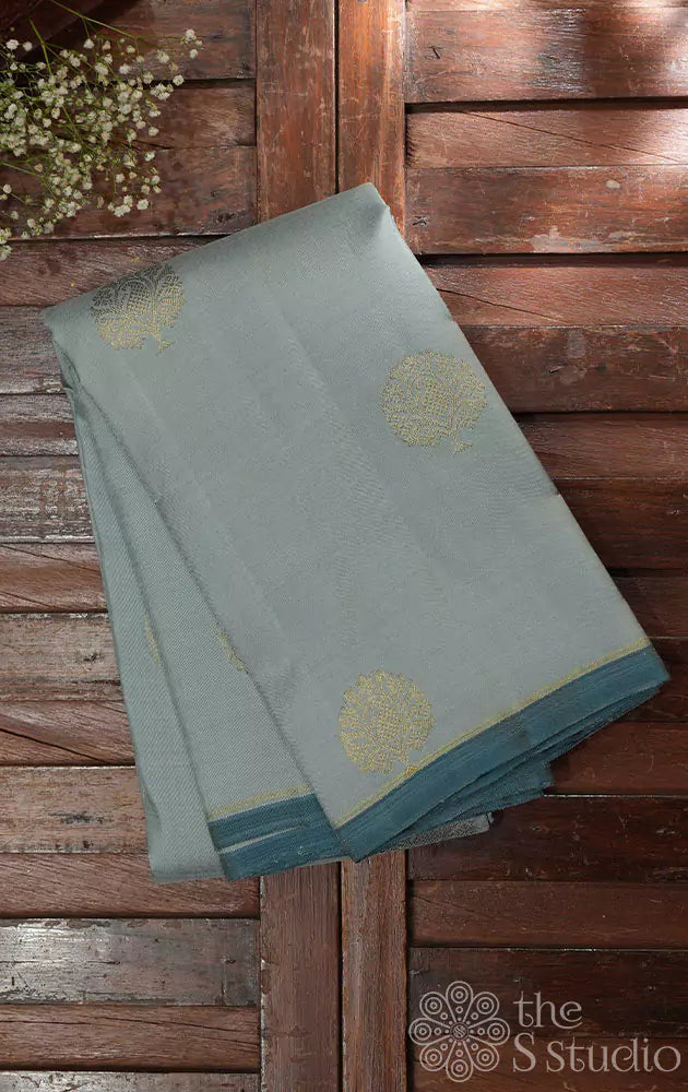 Teal grey kanjivaram saree with zari buttas and a teal blue pallu