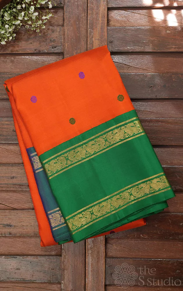 Orange korvai kanchi pattu saree with peacock blue and green border