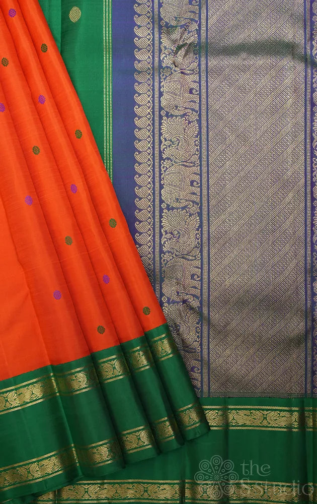 Orange korvai kanchi pattu saree with peacock blue and green border