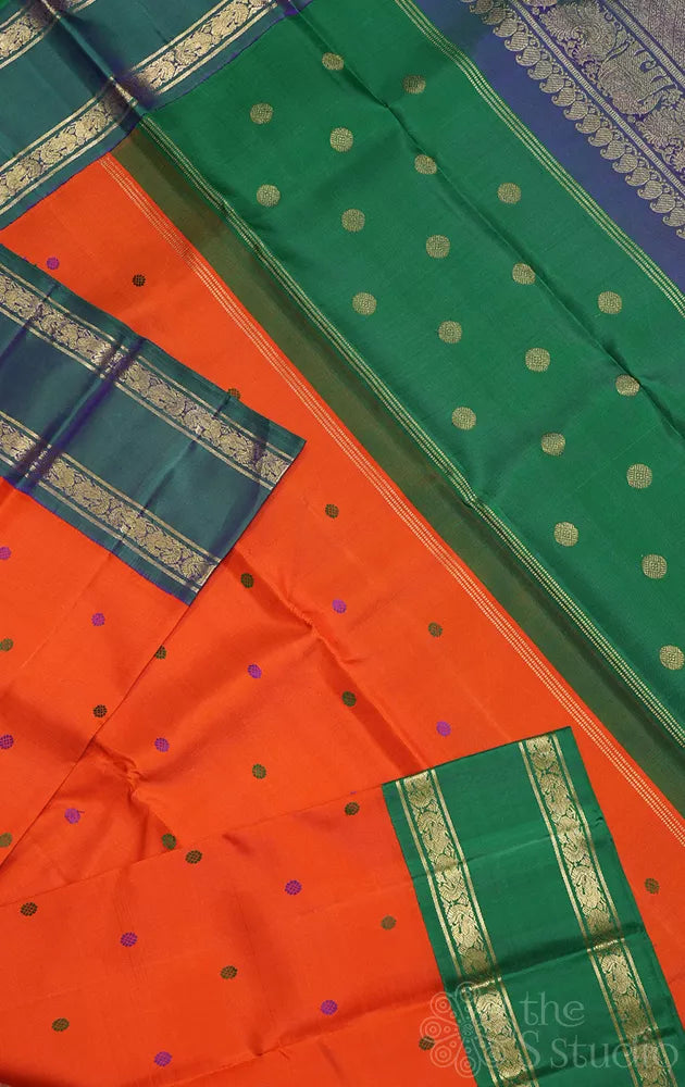 Orange korvai kanchi pattu saree with peacock blue and green border