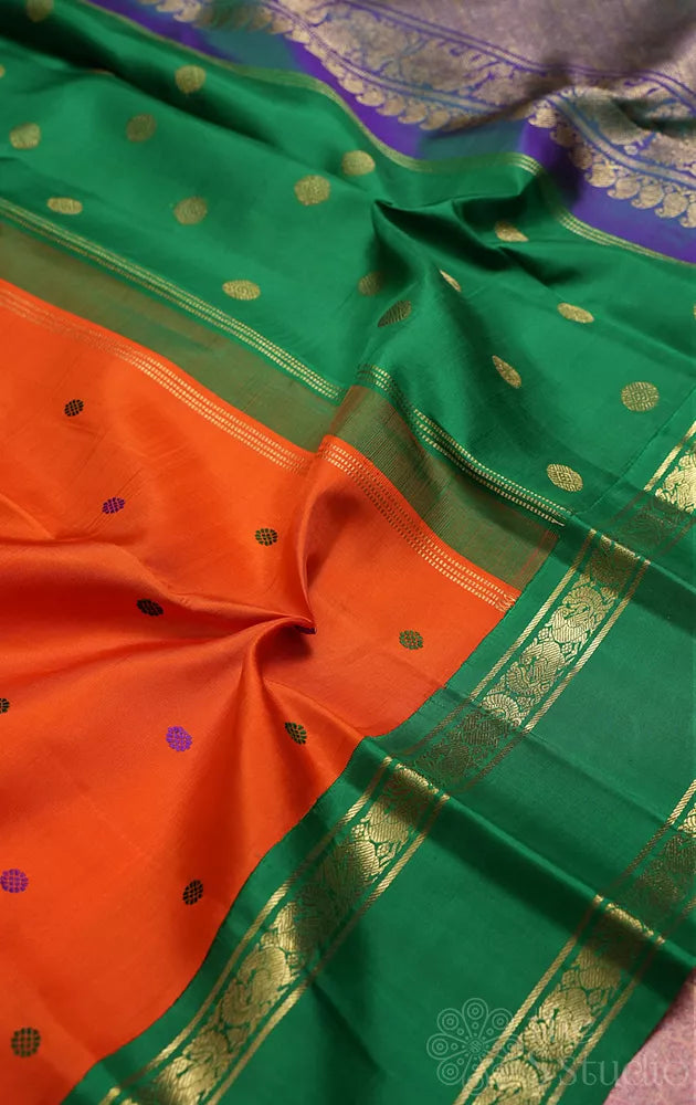 Orange korvai kanchi pattu saree with peacock blue and green border