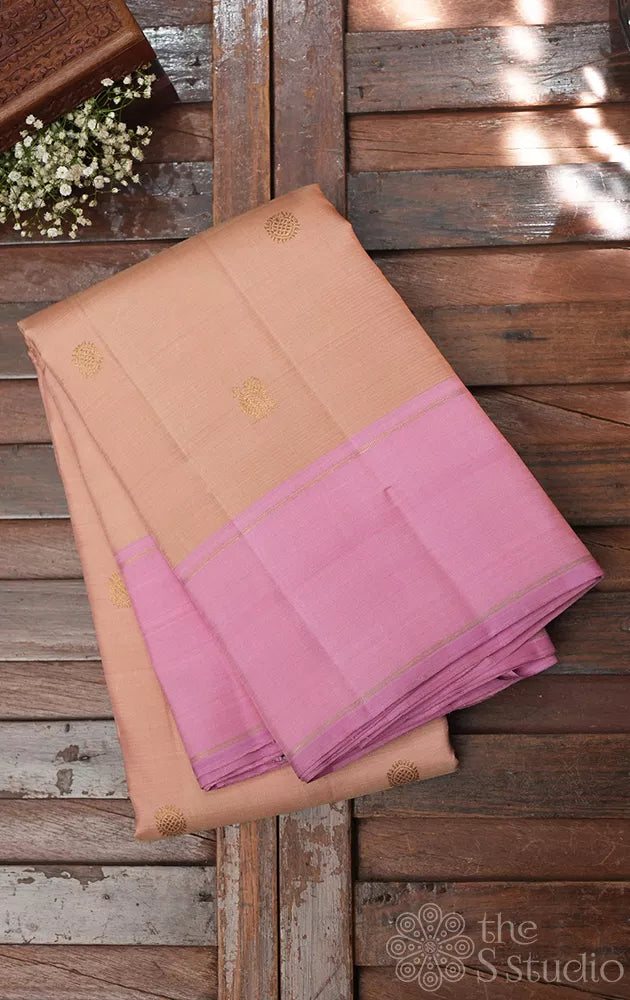 Light peach kanchi silk saree with zari bhuttas and pink border