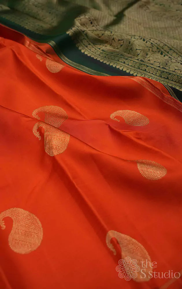 Bright orange kanchi silk saree with mango buttas and a contrast green pallu